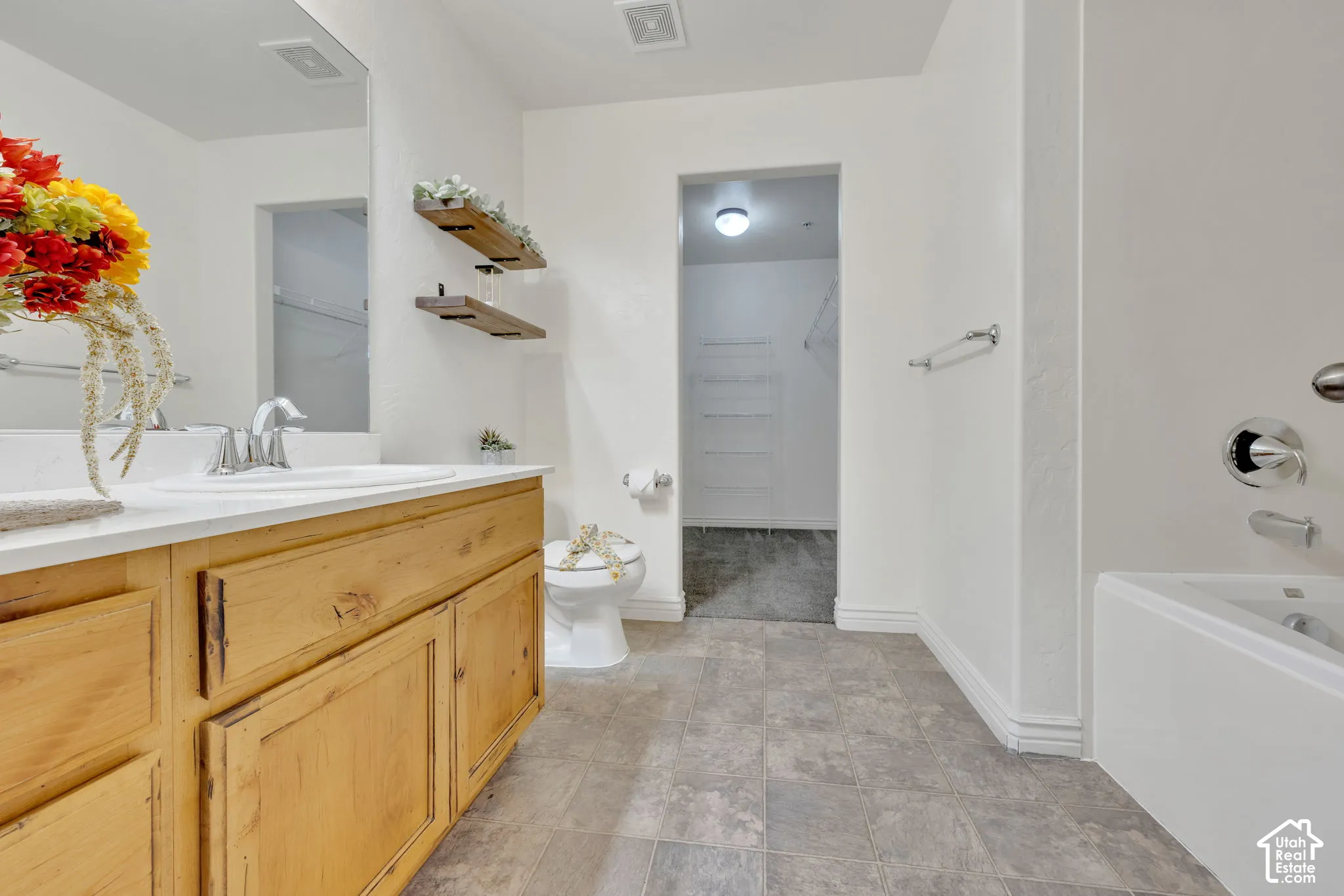 Bathroom featuring a built-in vanity with wood-finish cabinetry, a white countertop, and a white drop-in sink with a chrome faucet