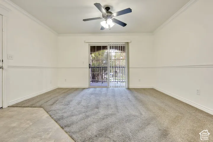 Plush carpet flooring, crown molding, chair rail detailing, sliding glass door, and a ceiling fan with integrated lighting