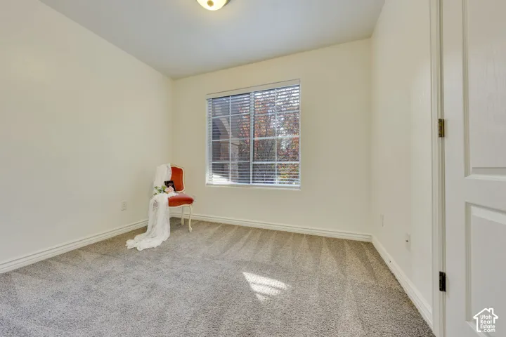 Bright, naturally lit bedroom with large picture window, neutral wall finishes, and soft carpet flooring