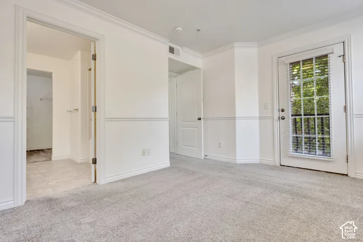 Plush carpeting, crown molding, wainscoting, and a glass-paneled door with blinds