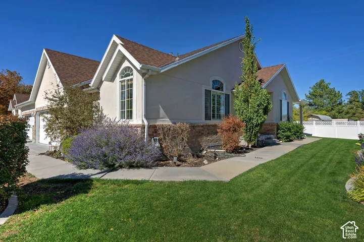Exterior featuring a stucco facade, brick accents, arched windows, a pitched roof, and an attached multi-car garage