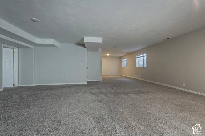 Expansive carpeted room with multiple windows, recessed lighting, and neutral wall finishes