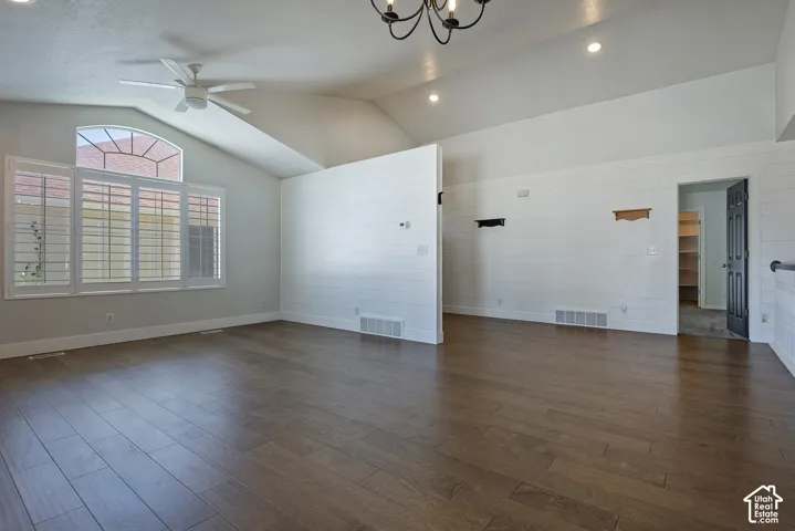 Spacious open-concept living area showcasing hardwood flooring, abundant natural light from shuttered windows, ceiling fan, recessed lighting, and white painted walls with neutral finishes throughout