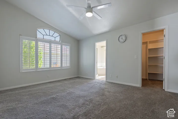 Vaulted ceiling with an arched transom window, plantation shutters, and a ceiling fan