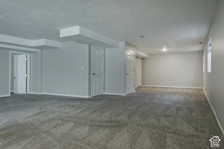 Expansive carpeted area with recessed lighting, light gray painted walls, and white paneled doors