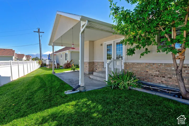Charming residence featuring a covered front porch with white columns and stone veneer accents, complemented by a manicured lawn and mature landscaping
