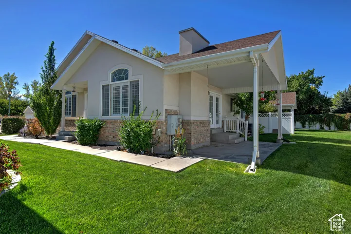 Exterior featuring a covered porch, brick wainscoting, stucco siding, and double French doors
