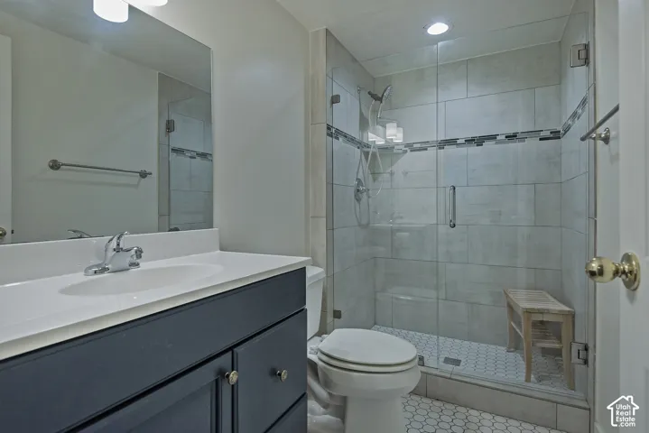 Vanity with a white countertop and oval undermount sink, chrome faucet, and dark-finish cabinetry