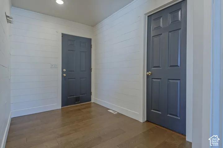 Wood-finish flooring with white shiplap walls and two paneled doors with gold-tone hardware