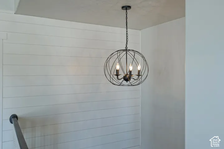 Orb-style chandelier with three candelabra bulbs, shiplap wall accent, smooth ceiling, and painted walls