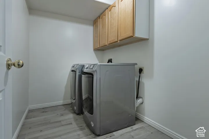Laundry area featuring wood-finish flooring and upper cabinetry