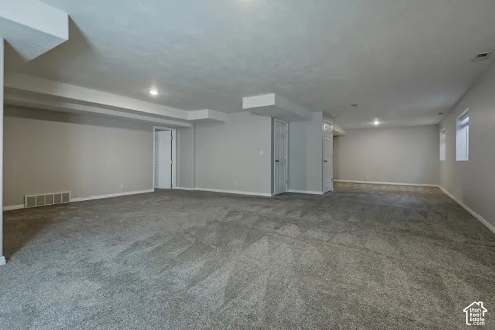 Spacious interior featuring gray carpeting, light gray walls, and recessed lighting