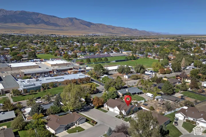 Expansive mountain backdrop with a residential setting, surrounded by mature trees and a clear sky