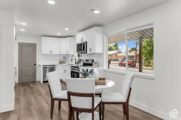 Modern kitchen featuring white shaker cabinetry, stainless steel appliances, wood-finish flooring, and recessed lighting