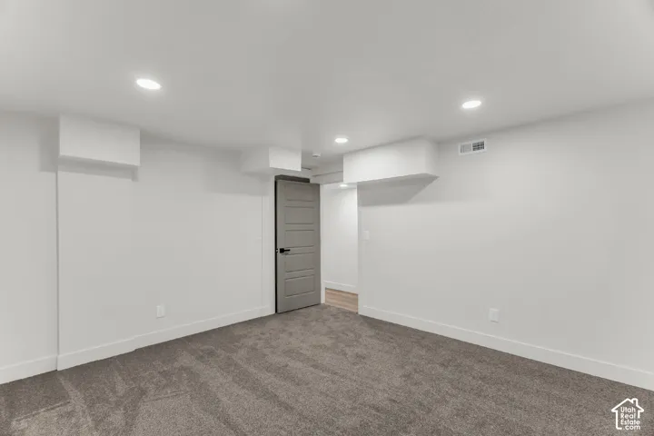 Neutral wall paint, recessed ceiling lighting, gray carpet flooring, contemporary interior door with black hardware, and white trim work