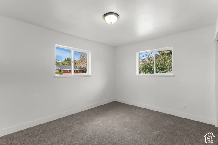 Neutral wall color with two windows, recessed lighting, and carpeted flooring