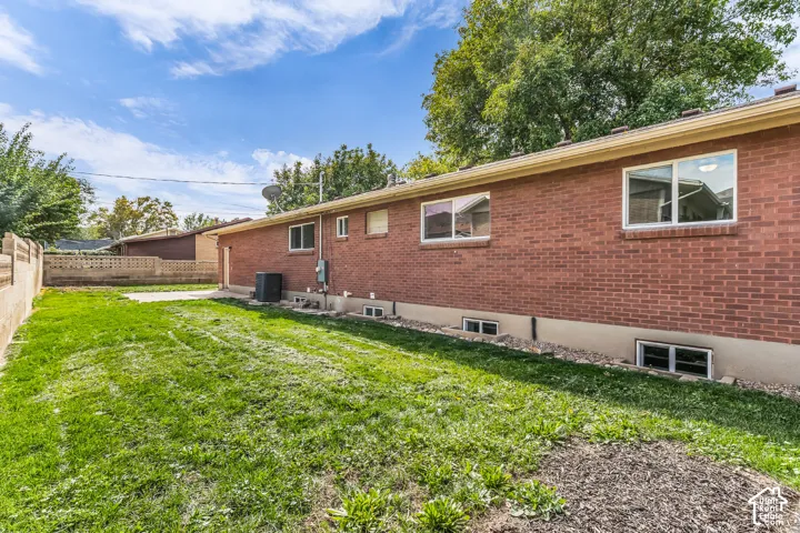 Brick exterior featuring multiple windows and a level lawn