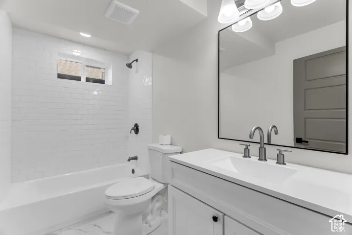 Integrated bathtub and shower with subway tile surround, white vanity with an undermount sink, wall-mounted mirror with a black frame, and brushed nickel fixtures
