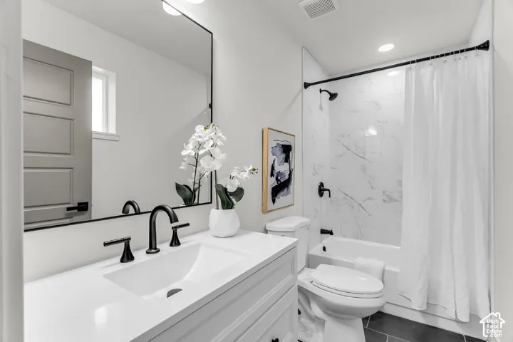 White vanity with undermount sink and matte black faucet, rectangular mirror, and an integrated bathtub with a tiled surround