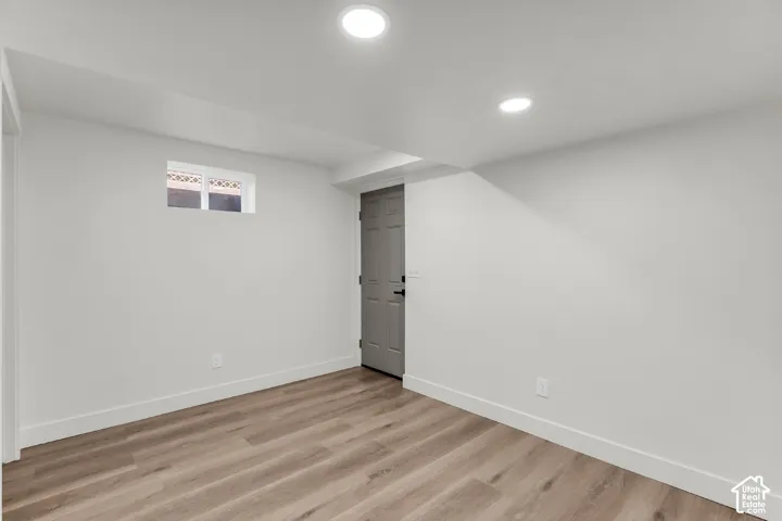 Recessed lighting, wood-finish flooring, white walls, white trim, and a gray door
