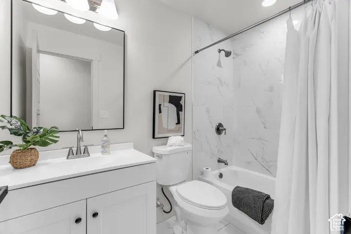 White vanity with integrated sink, rectangular framed mirror, three-light fixture, tub with shower, and patterned wall tile