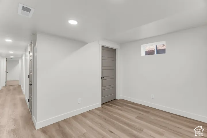 Recessed lighting, wood-finish flooring, white walls, gray interior doors, and a small window