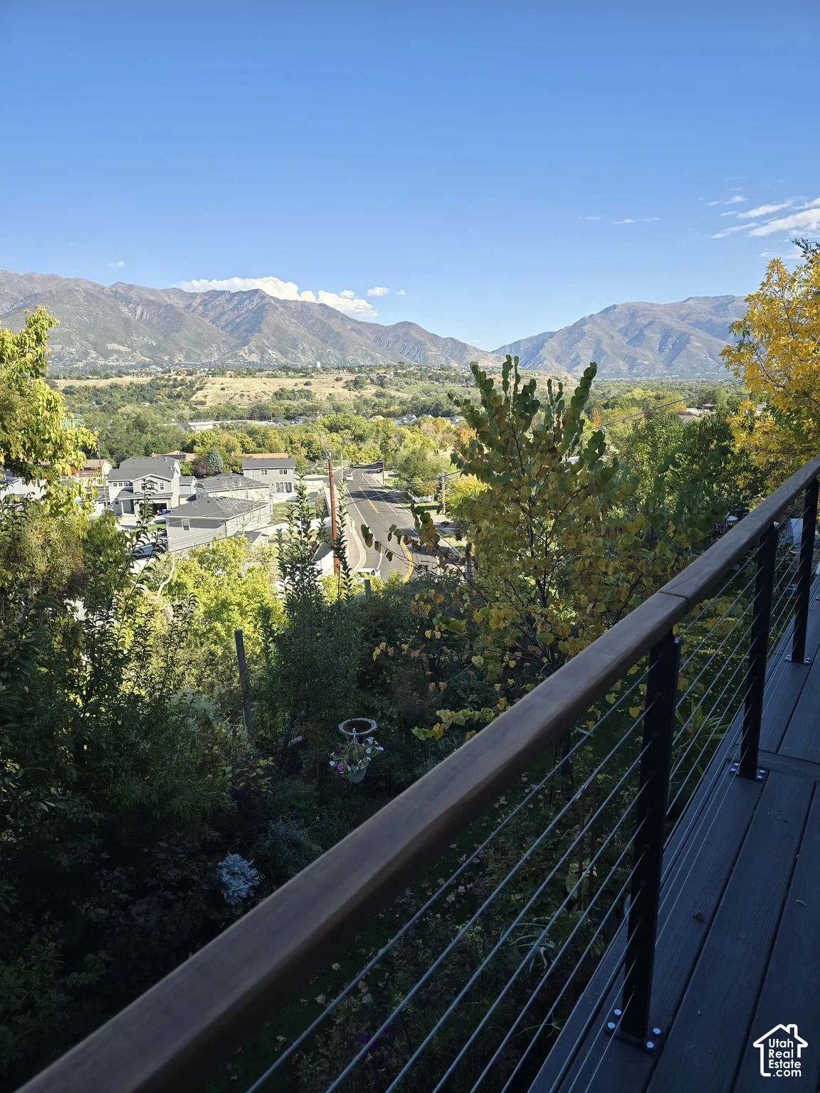 Outdoor deck with a cable railing system, overlooking a mountainous landscape and a residential area