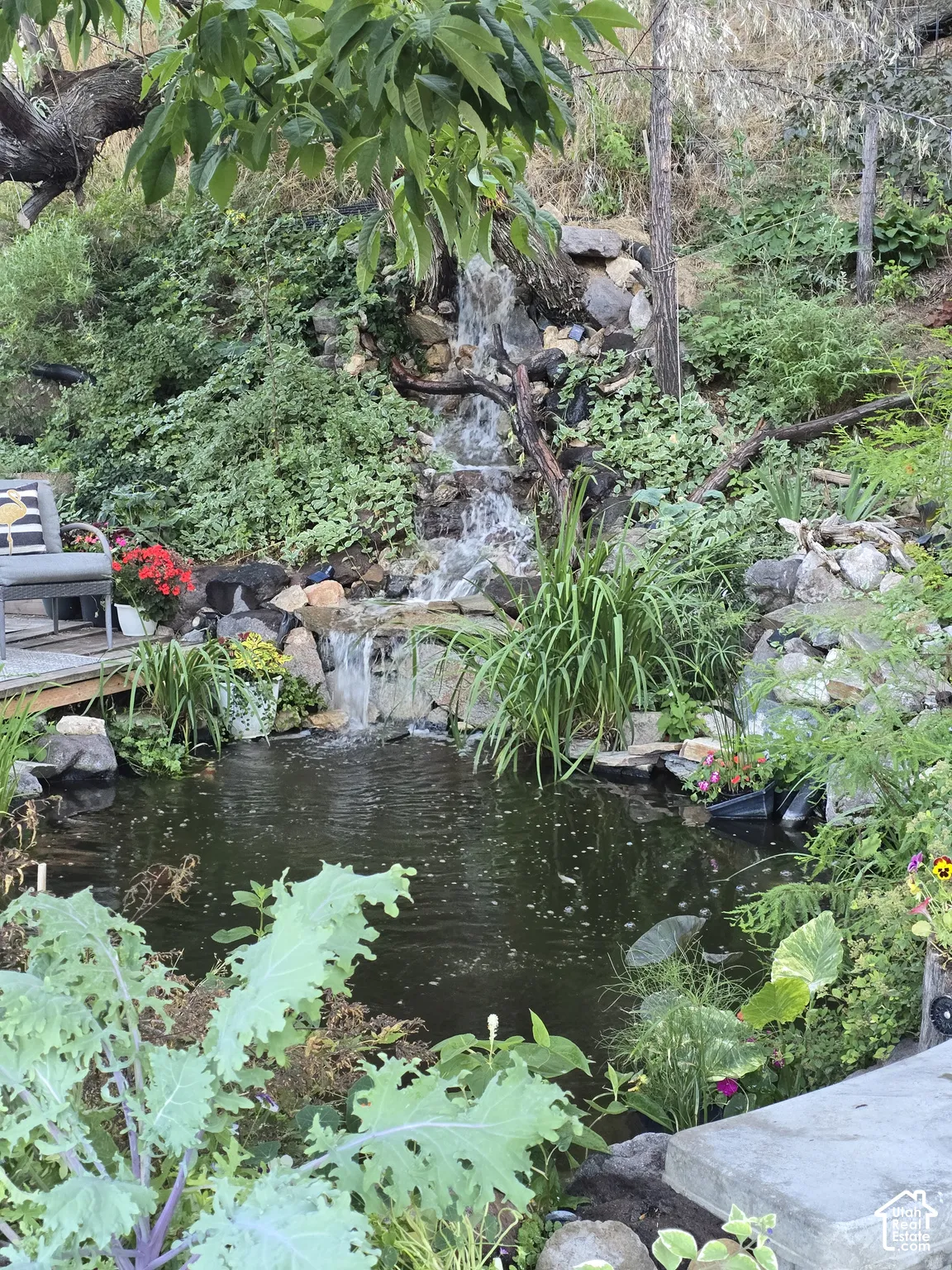 Expansive natural landscaping featuring a multi-tiered waterfall, a tranquil pond, and a stone-edged garden bed