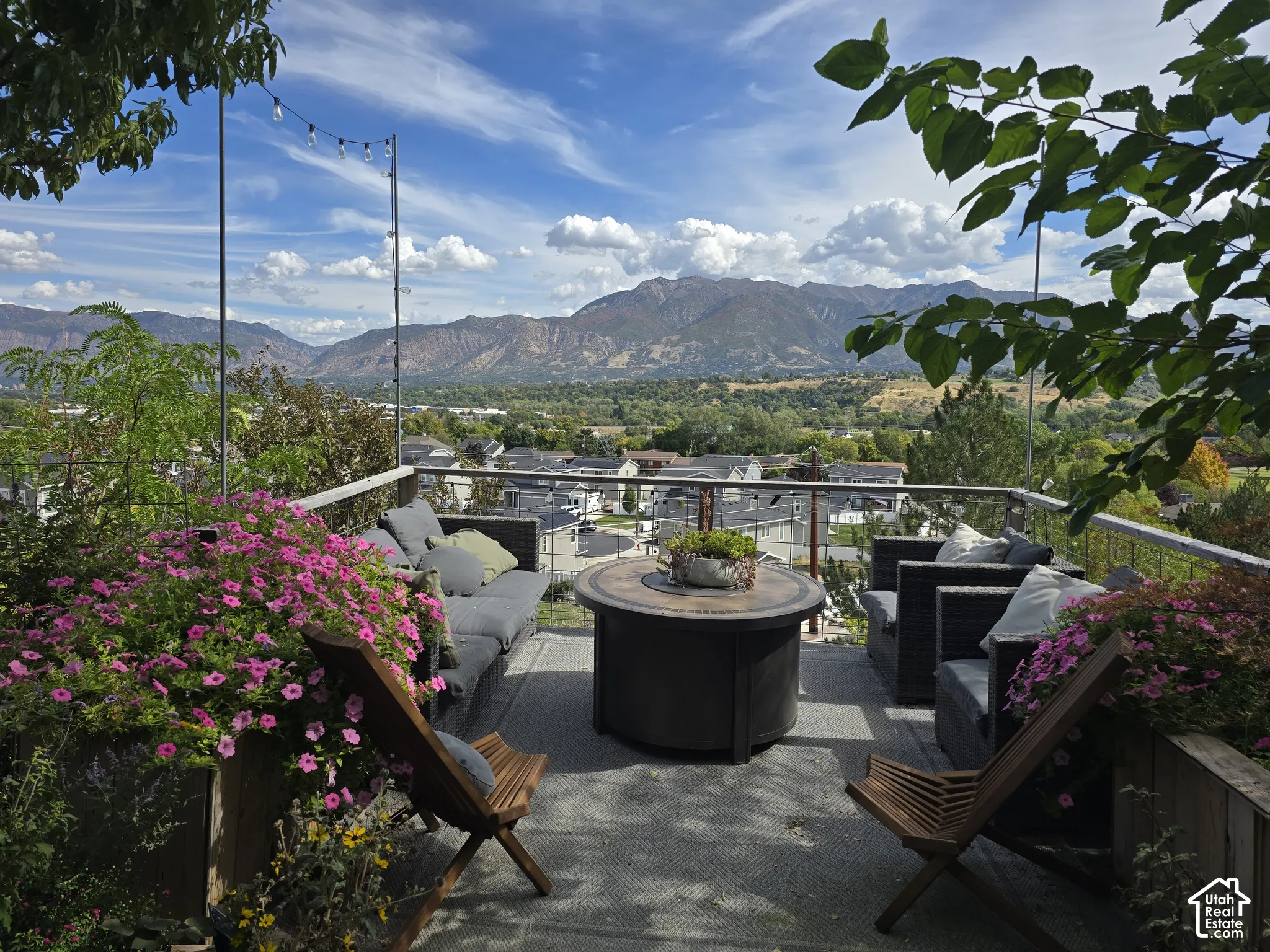 Expansive outdoor deck featuring a mountain backdrop, string lighting, and a glass railing