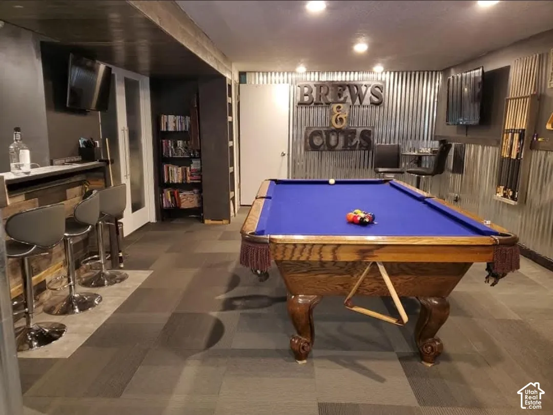 Recreational space featuring a built-in bar with wood-finish paneling, French-style double doors, and recessed lighting