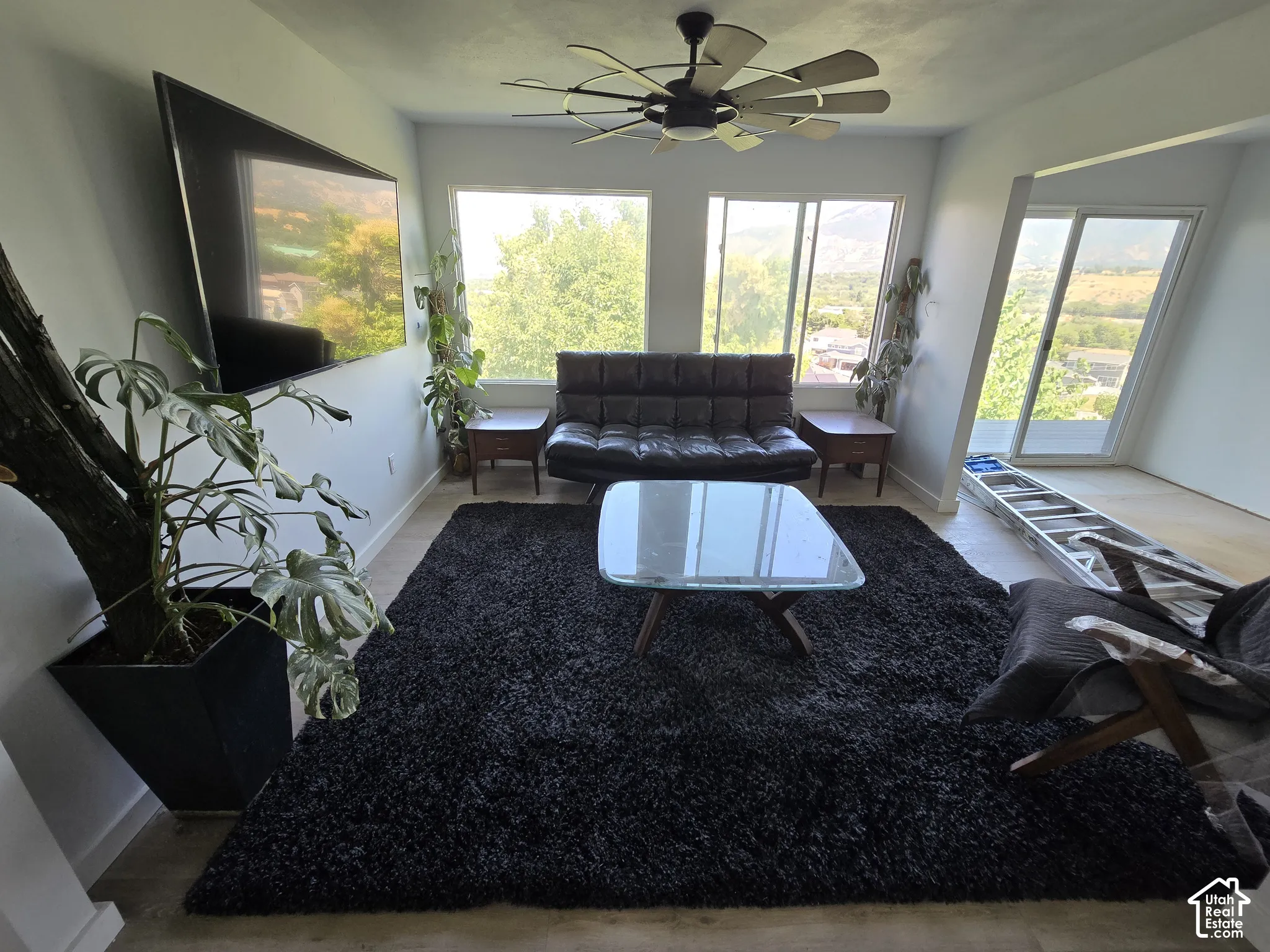 Light-filled living area featuring a ceiling fan, multiple windows, and a sliding glass door