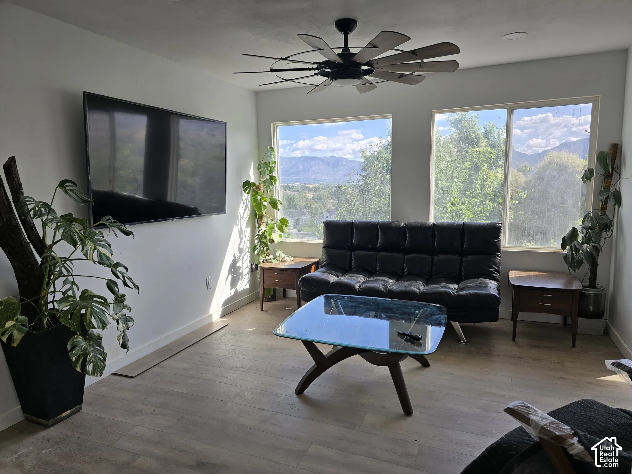 Expansive windows with mountain scenery, wood-finish flooring, and a ceiling fan