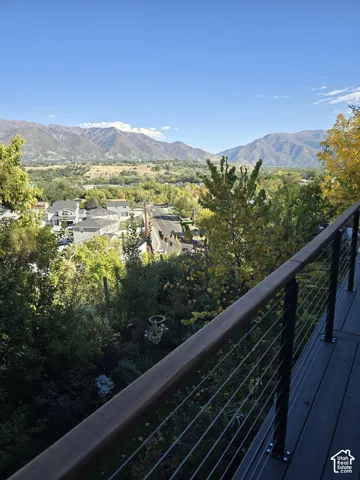 Outdoor deck with a cable railing system, overlooking a mountainous landscape and a residential area