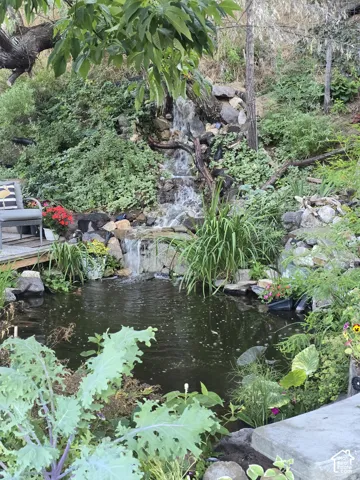 Expansive natural landscaping featuring a multi-tiered waterfall, a tranquil pond, and a stone-edged garden bed
