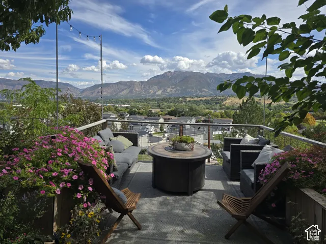 Expansive outdoor deck featuring a mountain backdrop, string lighting, and a glass railing