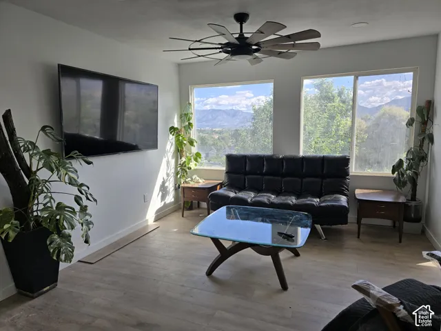 Expansive windows with mountain scenery, wood-finish flooring, and a ceiling fan