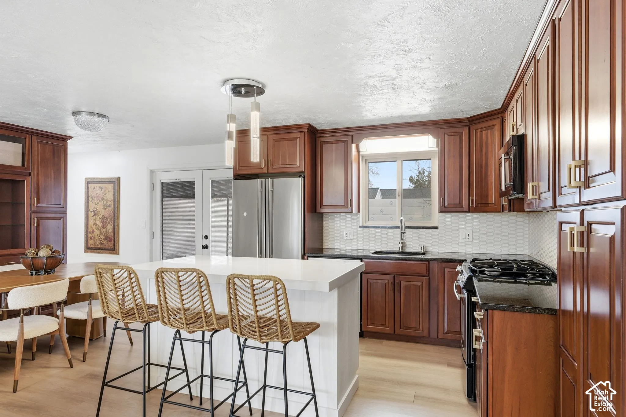 Kitchen featuring wood-finish cabinetry, stainless steel appliances, a center island with countertop seating, and light wood-finish flooring
