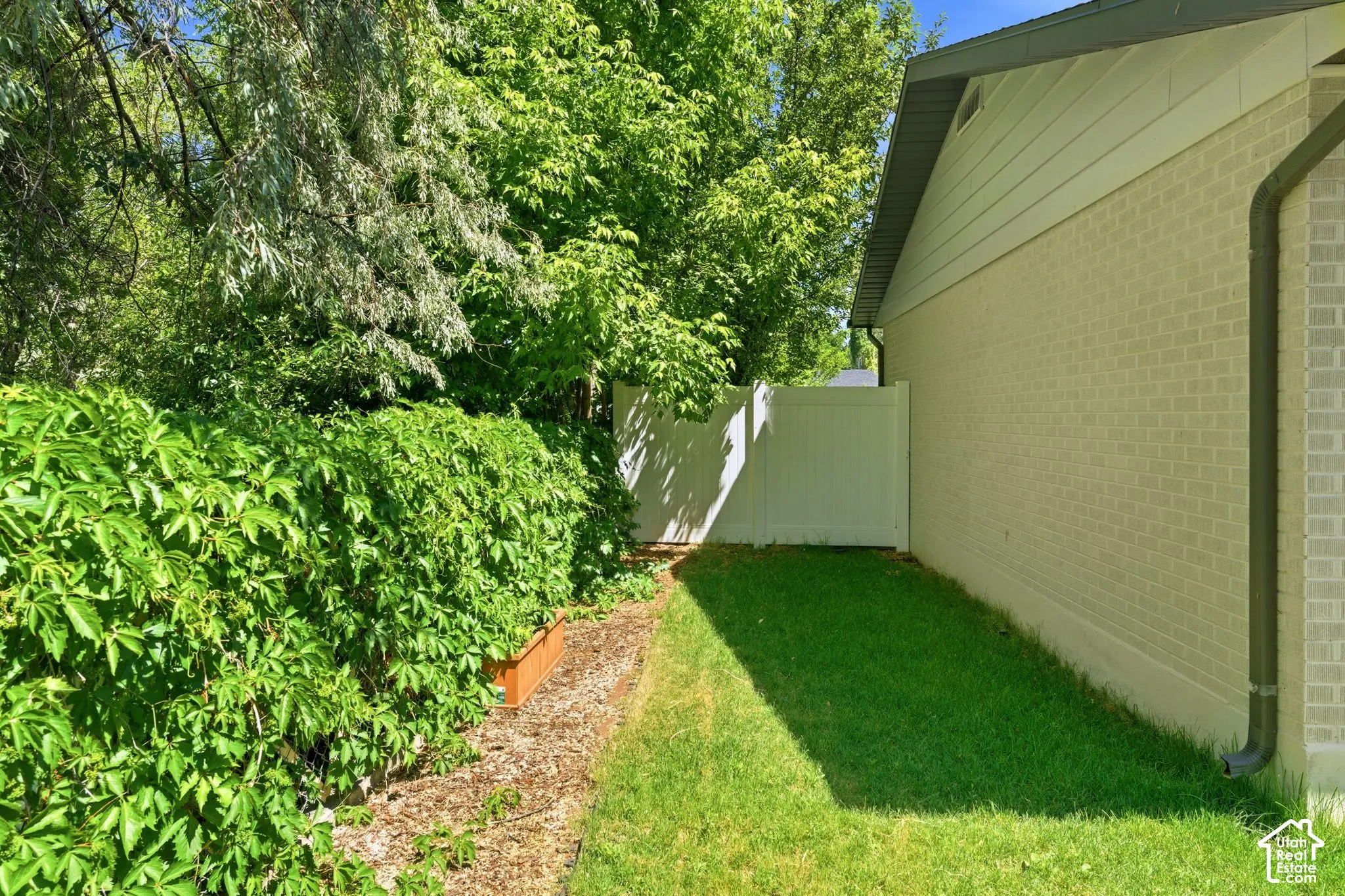 Manicured lawn area with a privacy fence and mature landscaping