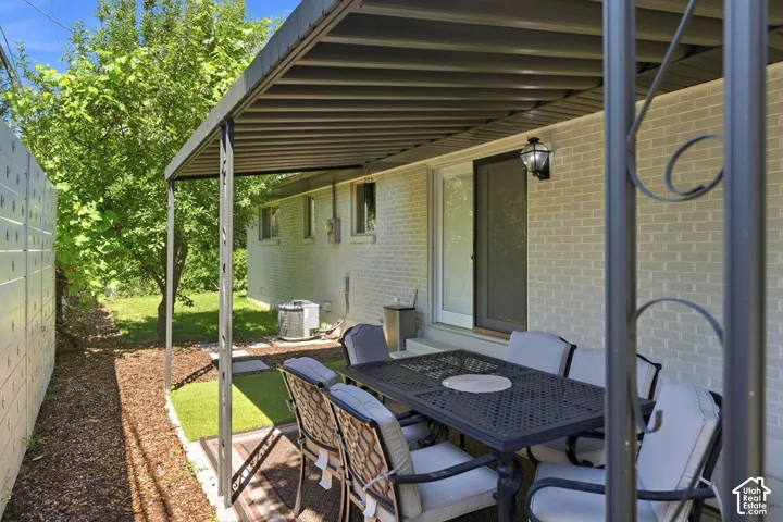Covered patio with a metal awning, featuring a sliding glass door and an exterior wall lantern