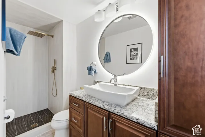 Shower with light-toned wall tile and dark floor tile, featuring a rain showerhead and hand shower
