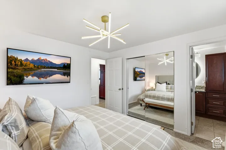 Modern ceiling light fixture, wall-mounted display, mirrored closet doors, and wood-finish cabinetry with a stone countertop