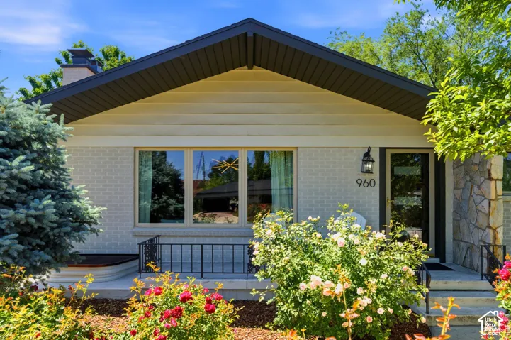 Brick and stone exterior with a prominent front entry, featuring a large picture window, an attached outdoor wall sconce, and a covered porch area