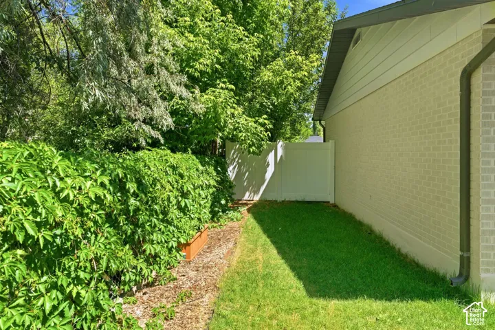 Manicured lawn area with a privacy fence and mature landscaping