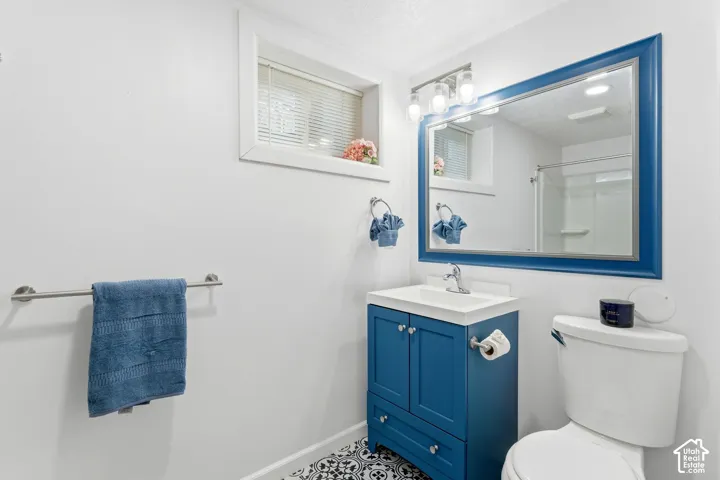 Modern bathroom featuring a blue vanity with a white countertop sink, a framed mirror, and patterned floor tiling