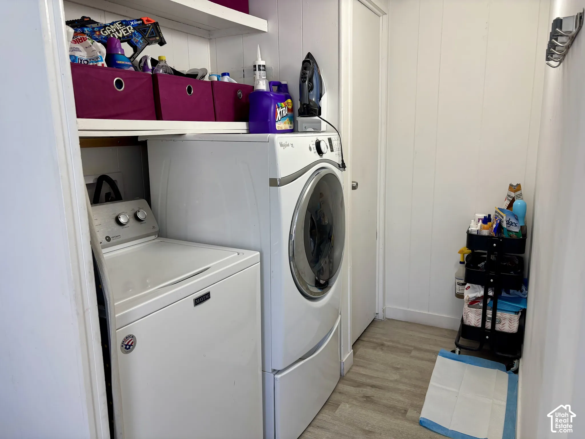 Utility area featuring a top-load washing machine, front-load dryer, and vertical paneling