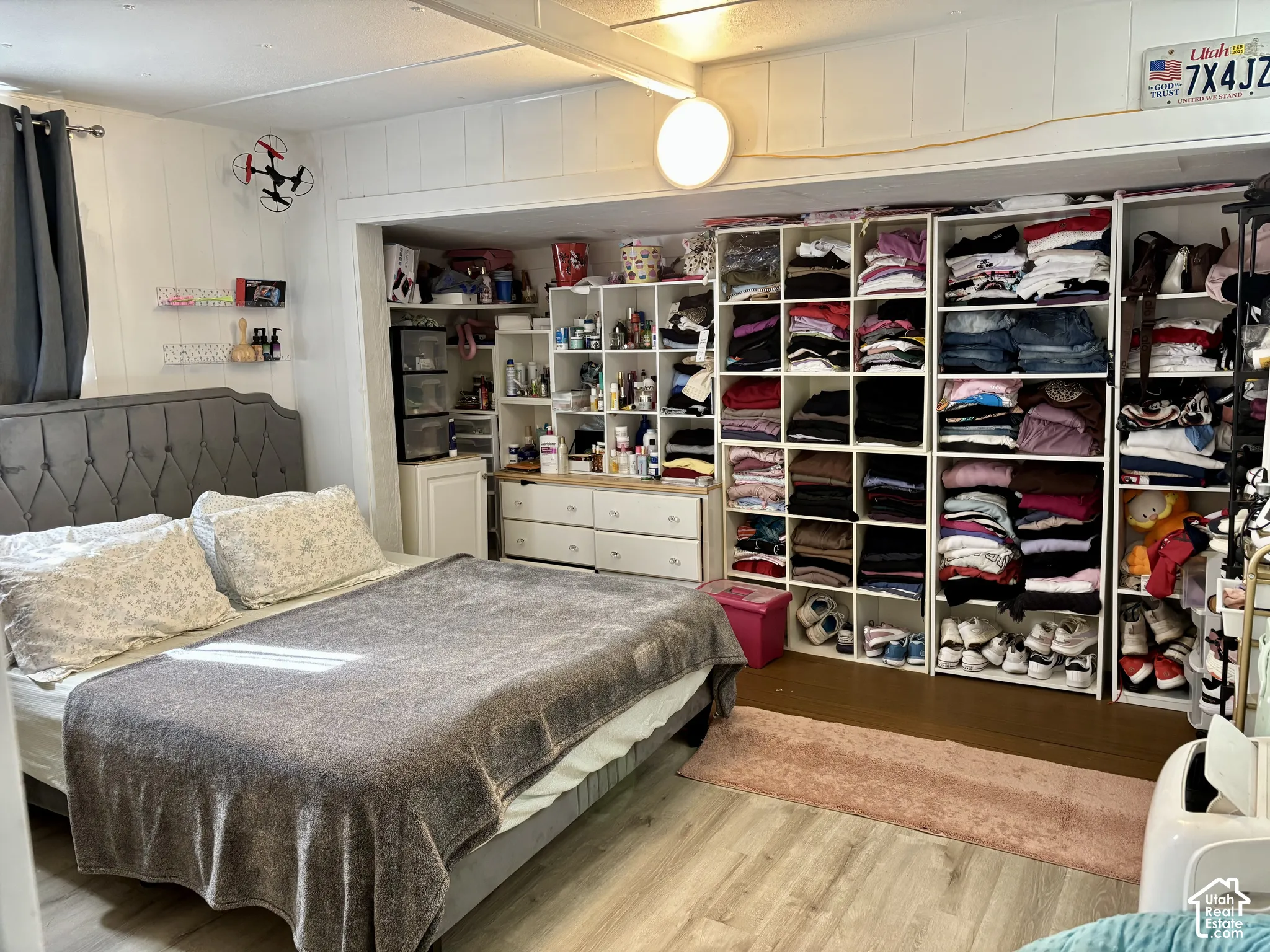 Wood-finish flooring, paneled walls, built-in shelving, recessed alcove, and a tufted headboard