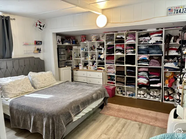 Wood-finish flooring, paneled walls, built-in shelving, recessed alcove, and a tufted headboard