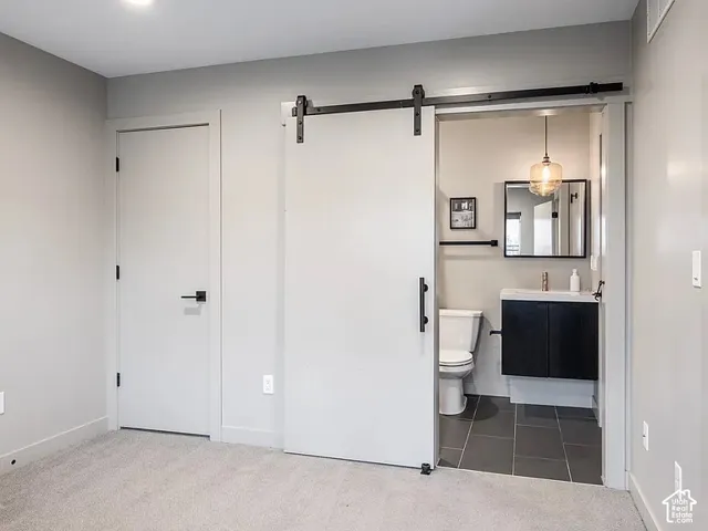 Modern barn door entry to a bathroom featuring a floating vanity with a dark wood-finish cabinet, a square framed mirror, and a globe pendant light fixture