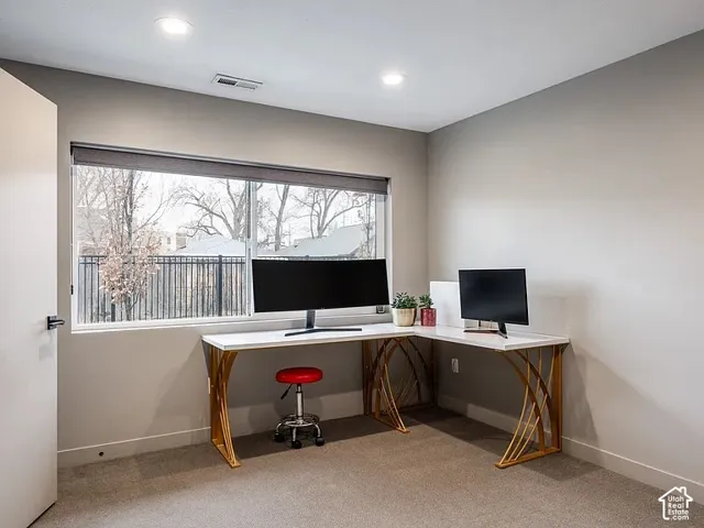 Carpeted room with recessed lighting and a wide window with roller shades