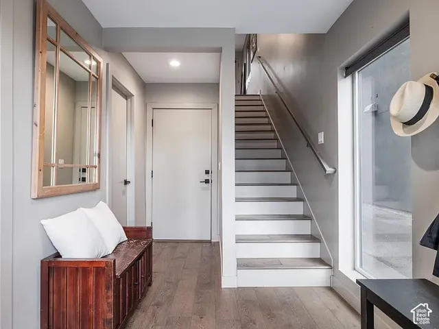 Wood-finish flooring throughout, with a windowed entryway and a staircase featuring white risers and wood-finish treads